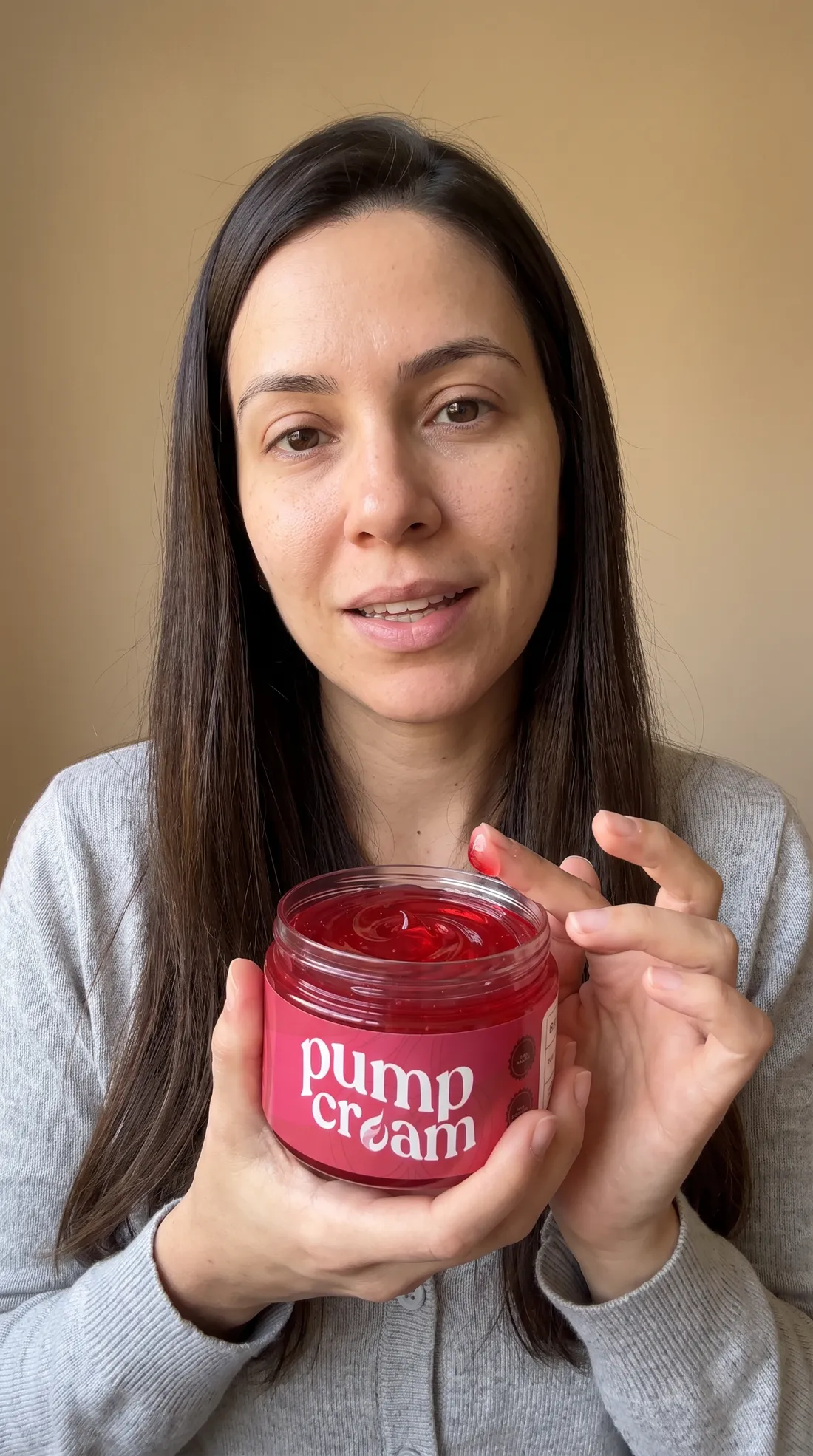 Mulher em casa mostrando para a câmera o pote aberto de Pump Cream com o gel vermelho